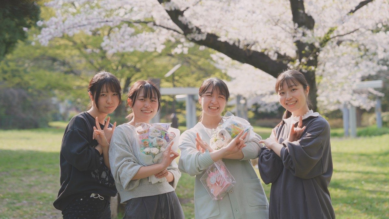 桜の下で花束を持つ4人