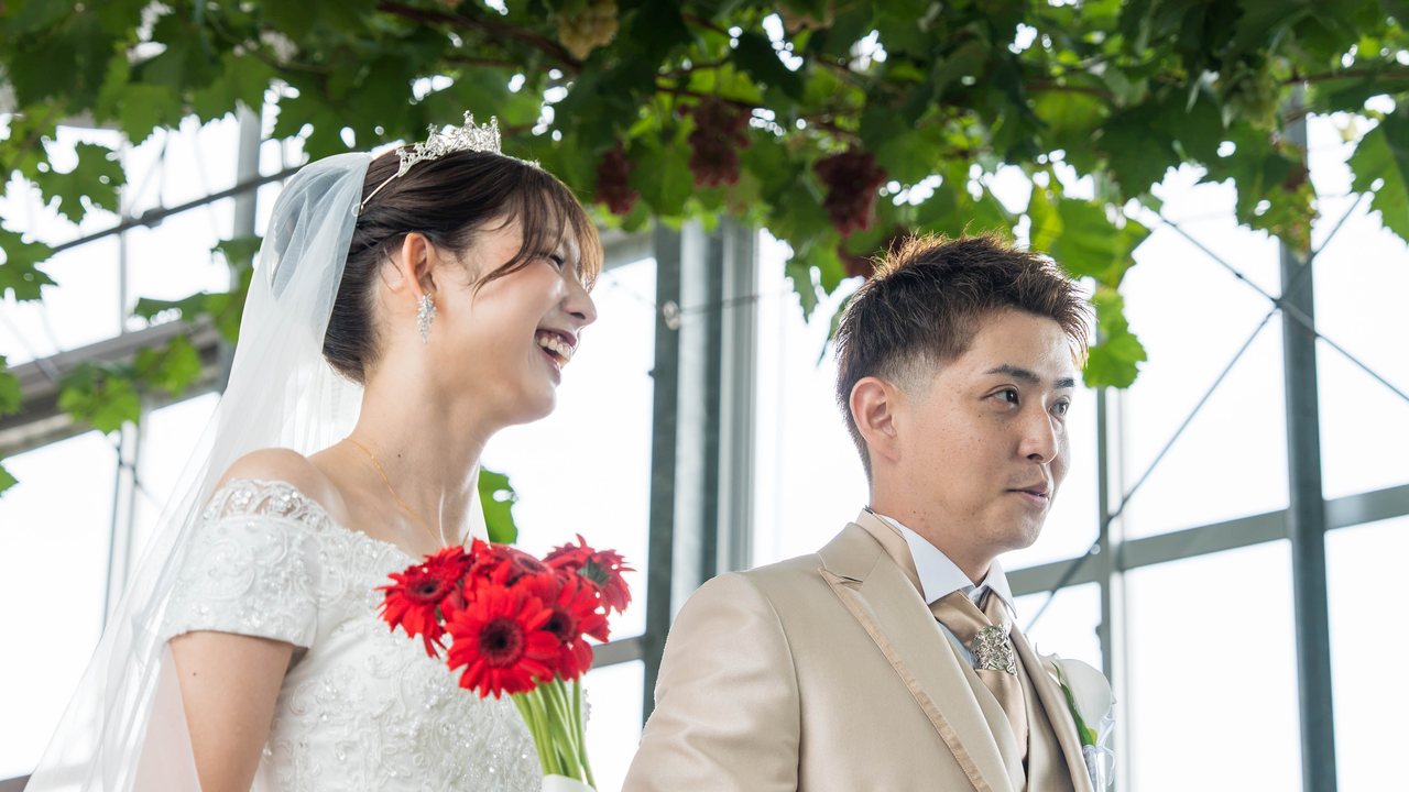 ぶどう棚の下で笑い合う新郎新婦