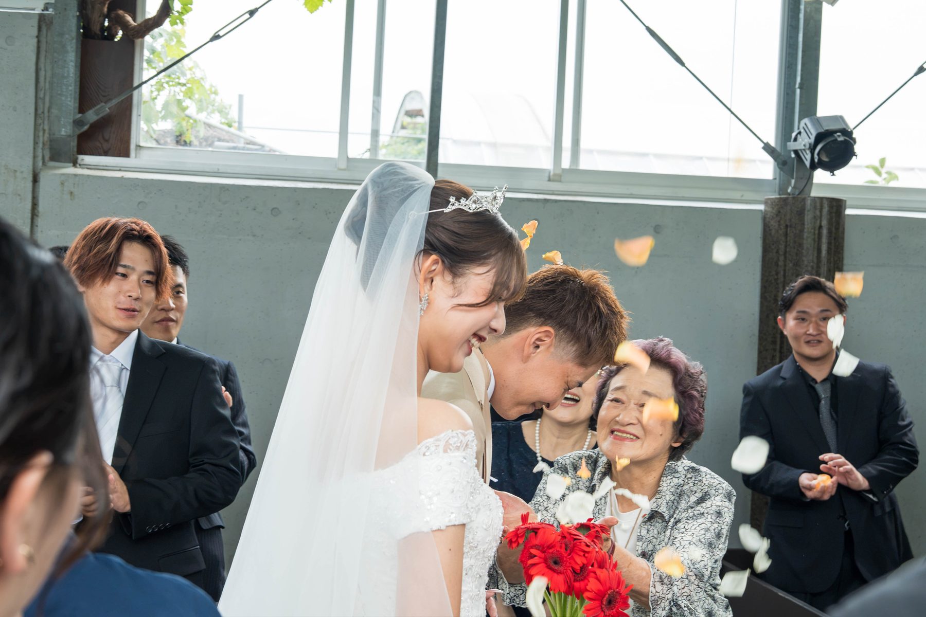 フラワーシャワーの中で笑う新婦と家族